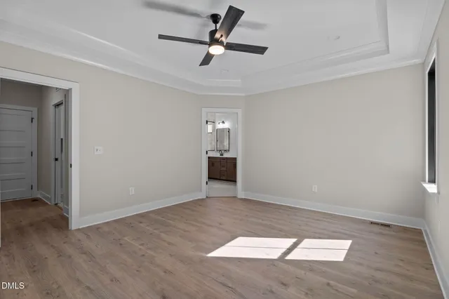 an empty room with wooden floor ceiling fan and windows