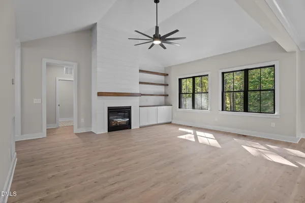 an empty room with windows and fireplace