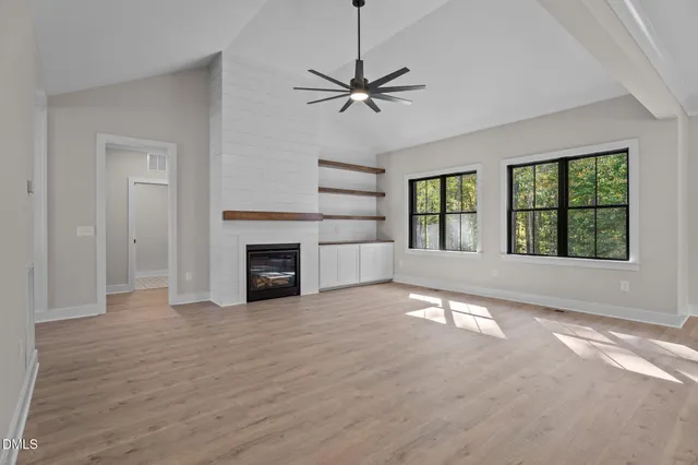 an empty room with windows and fireplace
