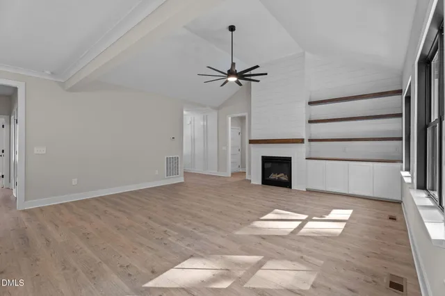 a view of a livingroom with a fireplace a ceiling fan and window
