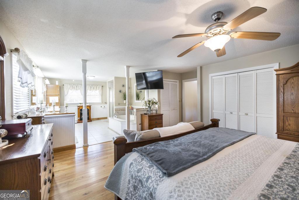 2574 Lower Hartley Bridge Road Byron, GA 31008 - Photo 18 of 45 a large bedroom with a large bed a chandelier with flat screen tv and couches