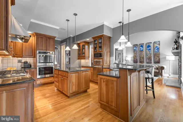 a kitchen with stainless steel appliances granite countertop a refrigerator a stove oven and a dining table with wooden floor