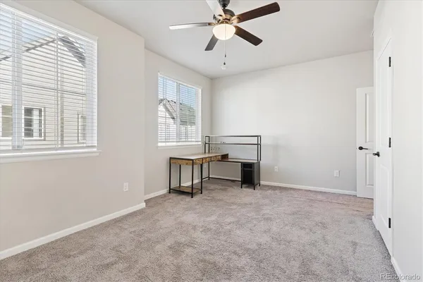 a view of an empty room with chandelier fan and a window