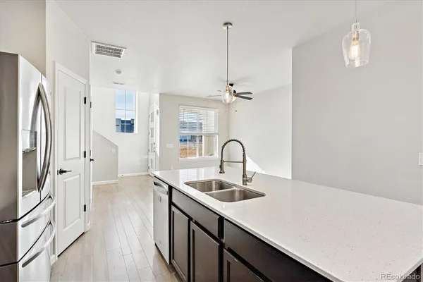 a kitchen with stainless steel appliances granite countertop a sink a refrigerator and a wooden floor