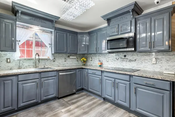 a kitchen with granite countertop a sink cabinets and stainless steel appliances