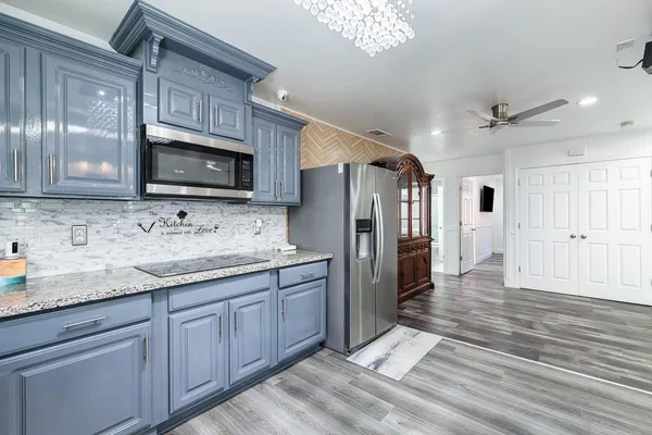 a kitchen with stainless steel appliances granite countertop a refrigerator oven a sink dishwasher and white cabinets with wooden floor