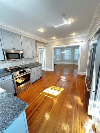 a kitchen with granite countertop stainless steel appliances a refrigerator cabinets and wooden floor