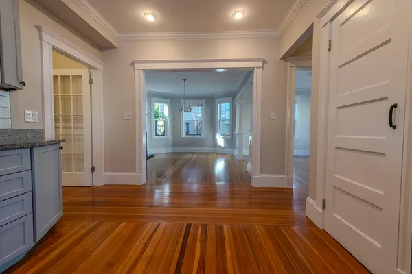 a view of an empty room with wooden floor fireplace and a window