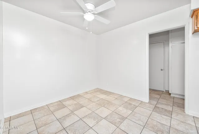 an empty room with white walls and fan