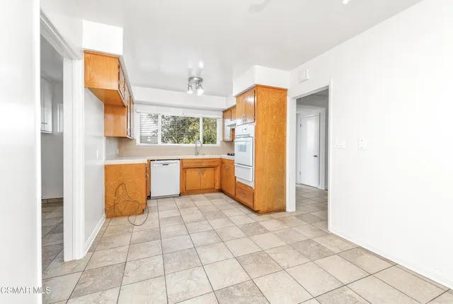 a kitchen with a cabinets a sink a window and stainless steel appliances