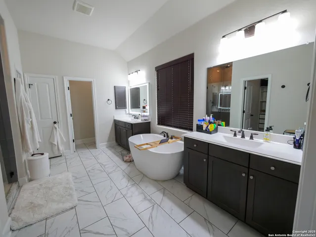 a spacious bathroom with a sink double vanity granite tub and mirror