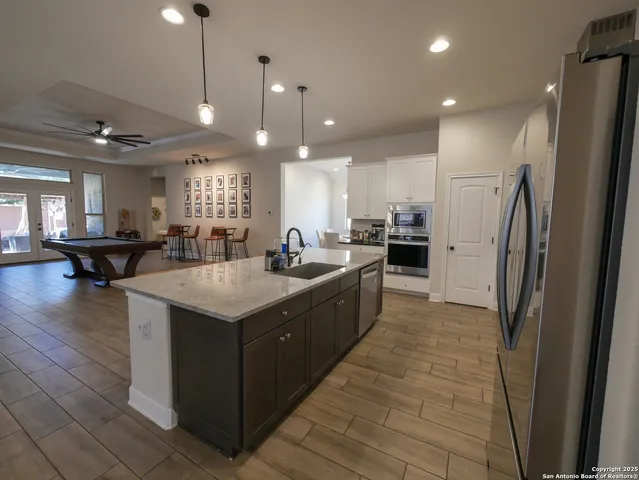 a kitchen with stainless steel appliances granite countertop a table chairs sink refrigerator and microwave
