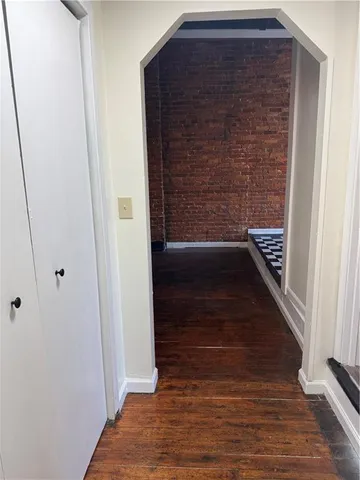 a view of an empty room with wooden floor and a fireplace