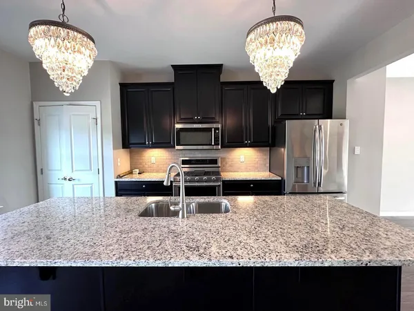 a kitchen with stainless steel appliances granite countertop a sink refrigerator stove and wooden floor