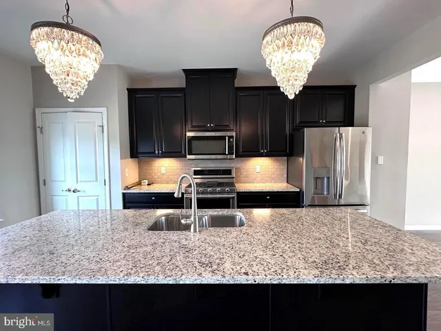 a kitchen with stainless steel appliances granite countertop a sink refrigerator stove and wooden floor