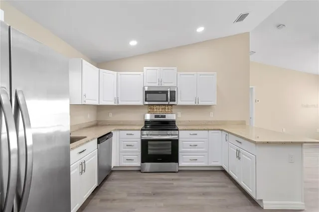 a kitchen with stainless steel appliances white cabinets and a stove top oven