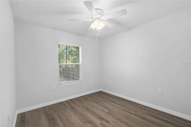 an empty room with wooden floor and a ceiling fan