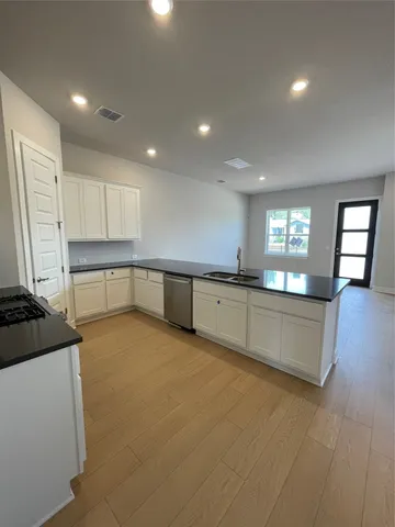 a large kitchen with stainless steel appliances granite countertop a lot of counter space and wooden floors