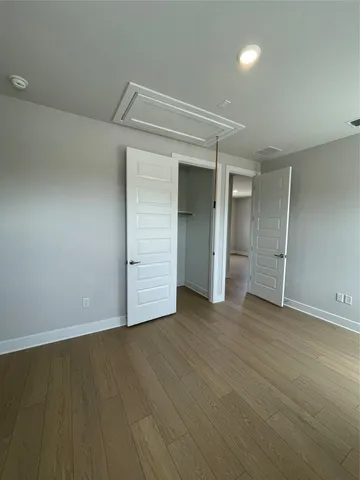 an empty room with wooden floor & closet area