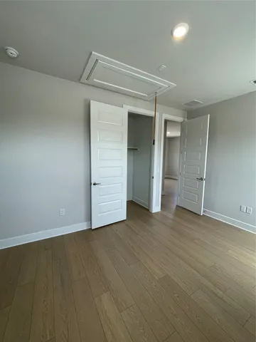 an empty room with wooden floor & closet area