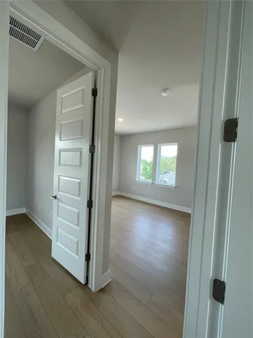 a view of a hallway with closet and wooden floor