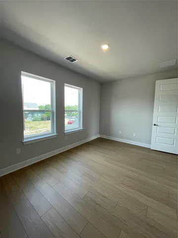 an empty room with wooden floor and windows