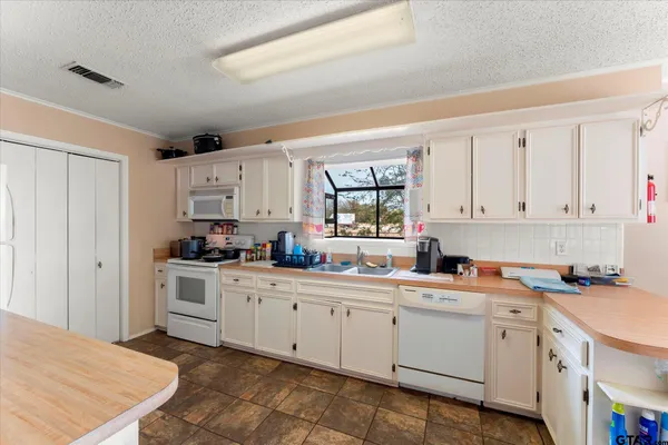 a kitchen with white cabinets sink and white appliances