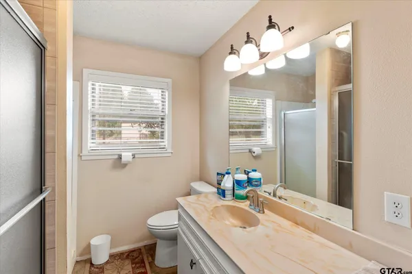a bathroom with a granite countertop sink mirror vanity and toilet