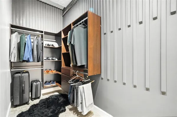 a view of walk in closet with clothes and shoes