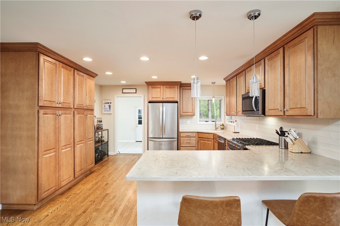 2530 Holgate Road Akron, OH 44313 - Photo 12 of 31 Kitchen featuring appliances with stainless steel finishes, a peninsula, light wood finished floors, backsplash, and recessed lighting