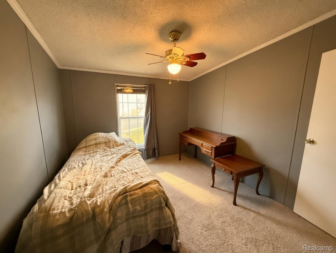 6988 McKean Road Ypsilanti, MI 48197 - Photo 9 of 21 Bedroom with carpet flooring, a textured ceiling, a ceiling fan, a decorative wall, and crown molding