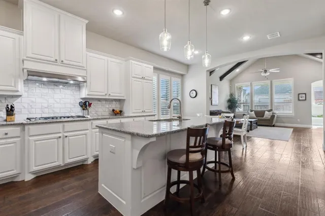 a large kitchen with cabinets chairs and wooden floor
