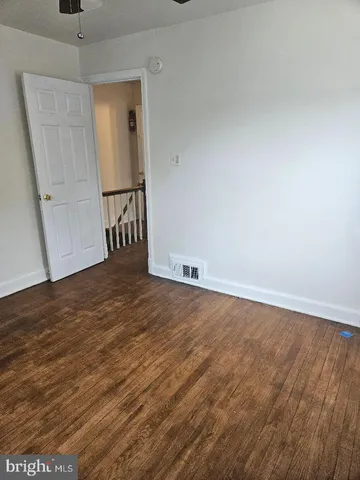 an empty room with wooden floor and a ceiling fan