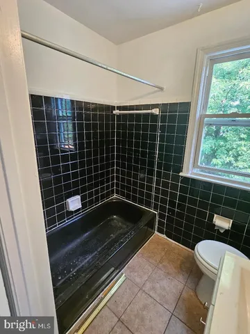 a bathroom with a toilet a sink a window and wooden floor