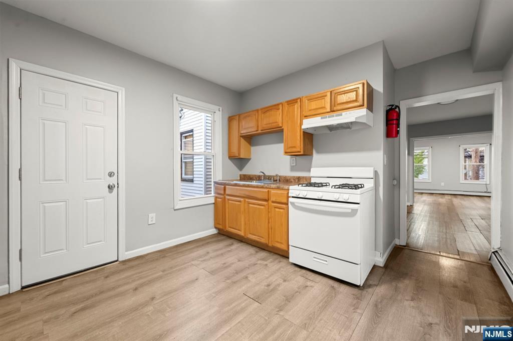 282 Hamilton Avenue Paterson, NJ 07501 - Photo 6 of 21 a kitchen with wooden floors and white appliances