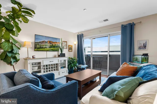 a living room with furniture a flat screen tv and a floor to ceiling window