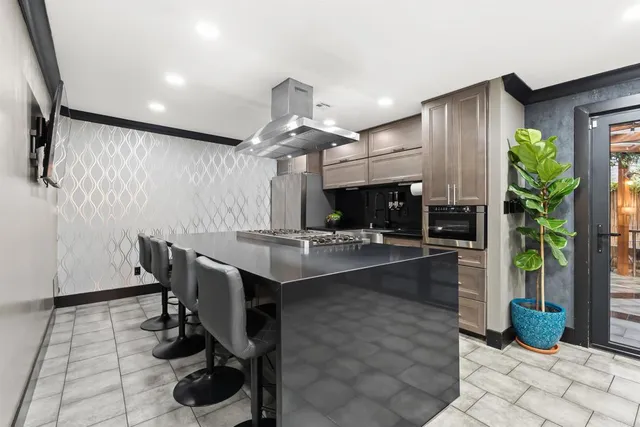 a kitchen with stainless steel appliances kitchen island granite countertop a refrigerator a sink a dining table and chairs with the view of kitchen