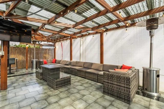 a living room with patio furniture and a grill