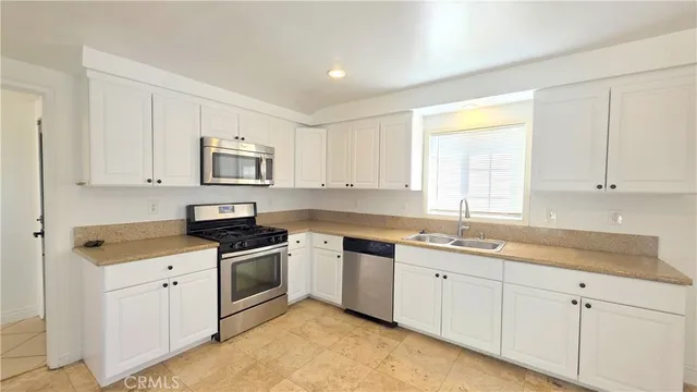a kitchen with cabinets appliances a sink and a window