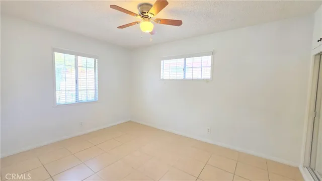 an empty room with windows and fan