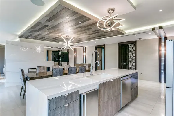 a room with stainless steel appliances kitchen island granite countertop a table chairs and a chandelier