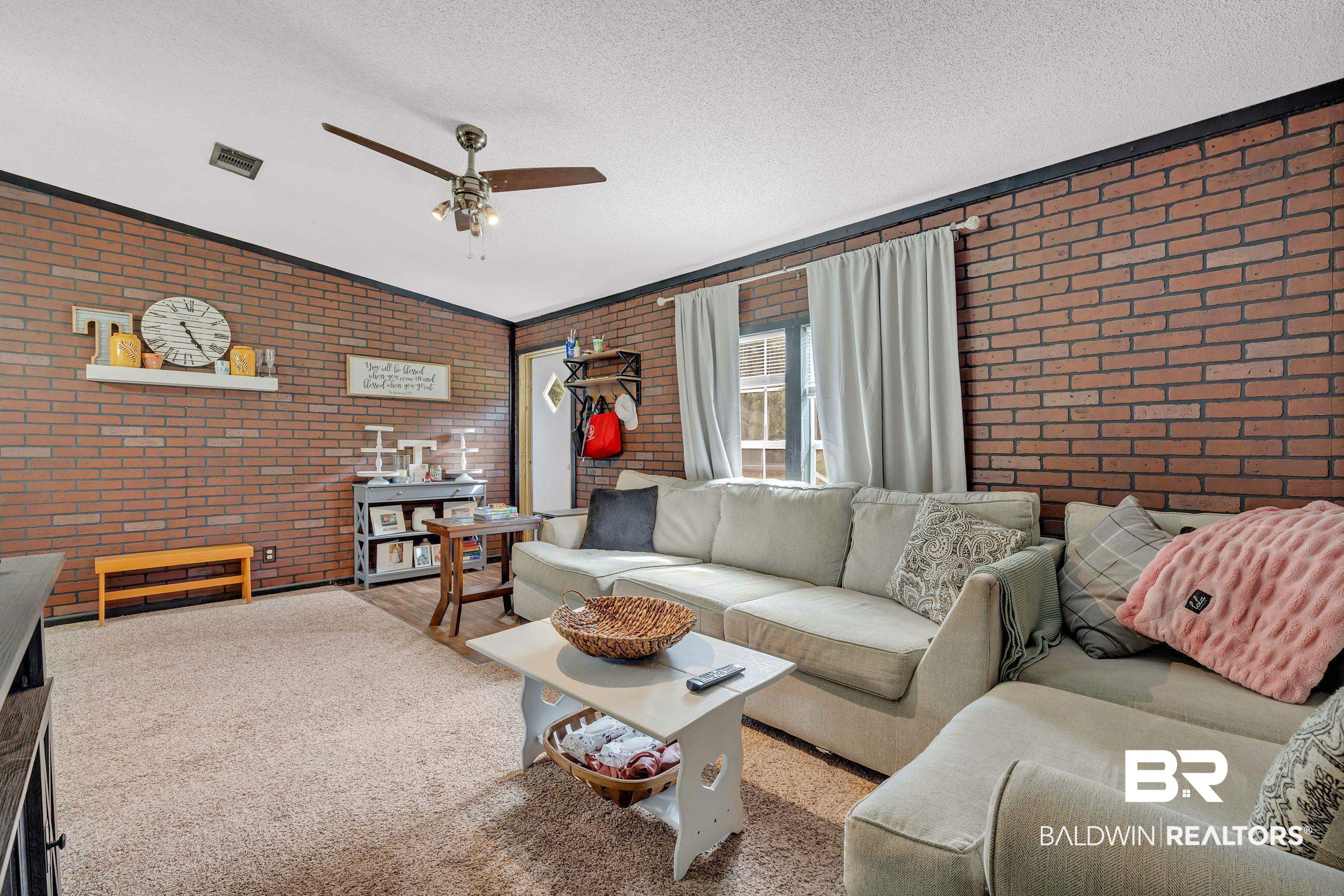22823 Lanier Road Robertsdale, AL 36567 - Photo 40 of 46 Living area with brick wall, a textured ceiling, a ceiling fan, and wood finished floors