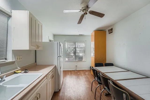 a kitchen with a stove a refrigerator a sink a dining table and chairs with wooden floor