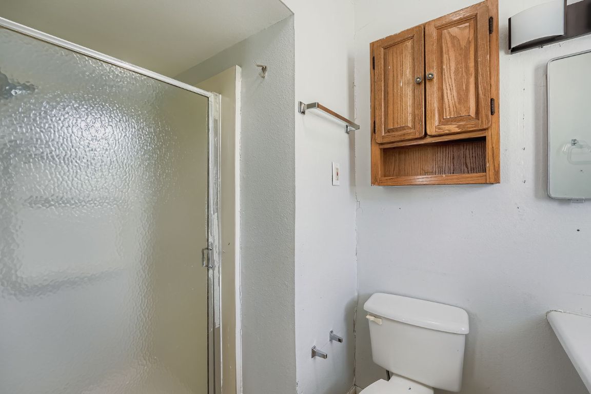 700 Blanco Street Kyle, TX 78640 - Photo 16 of 29 a bathroom with a granite countertop toilet and a shower