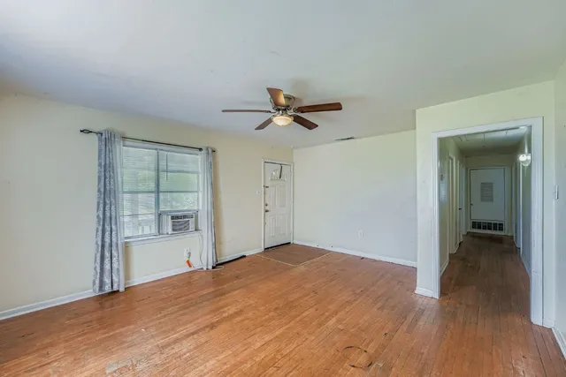 a view of empty room with wooden floor and ceiling fan