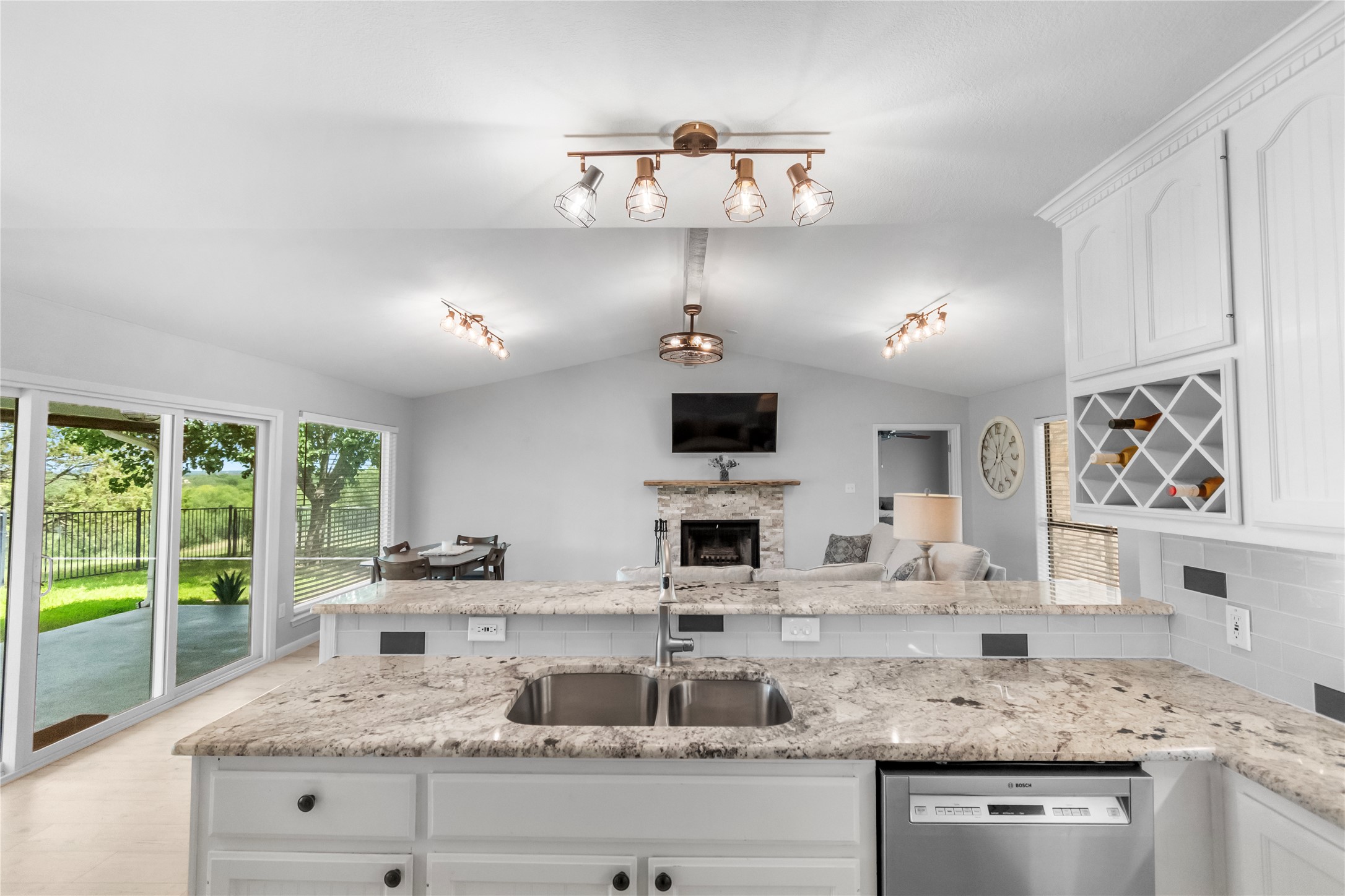 210 Teeoff, Unit B Horseshoe Bay, TX 78657 - Photo 12 of 38 A well-lit kitchen with granite counters and a pass-through to a vaulted great room with a stone fireplace.