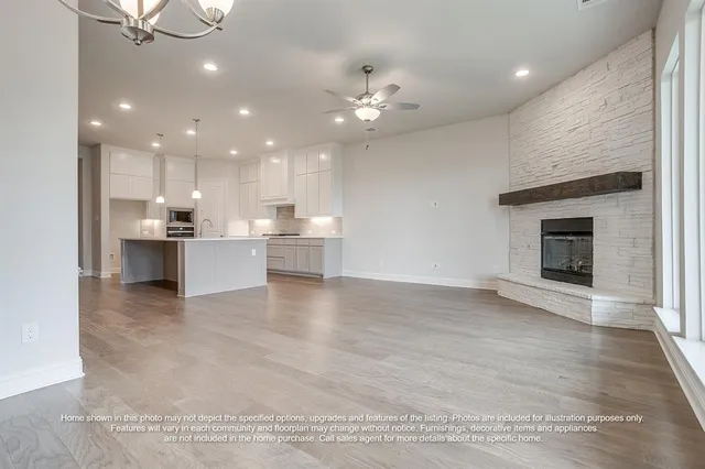 a view of an empty room and kitchen with fireplace cabinet