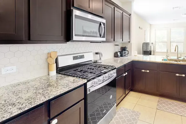 a kitchen with stainless steel appliances granite countertop a stove a sink and a microwave