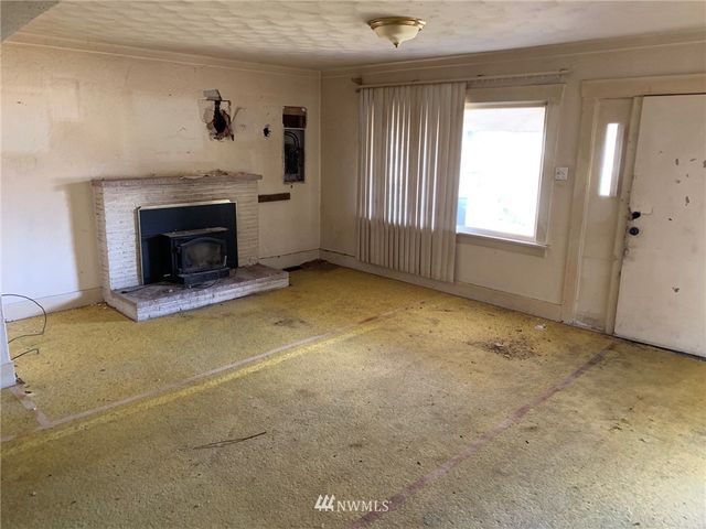 an empty room with windows and fireplace