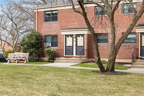 a view of a brick house with large windows and a yard